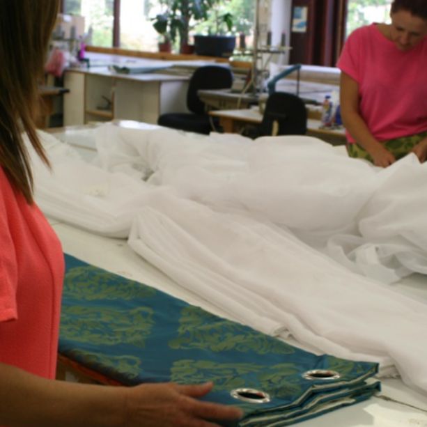 A lady works a table with fabrics that she is folding.