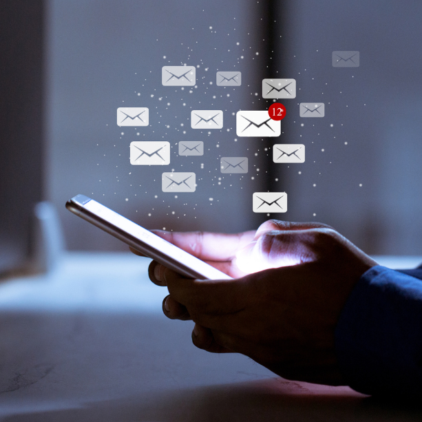 A close up of someone using their phone with graphics of email envelopes flying out.