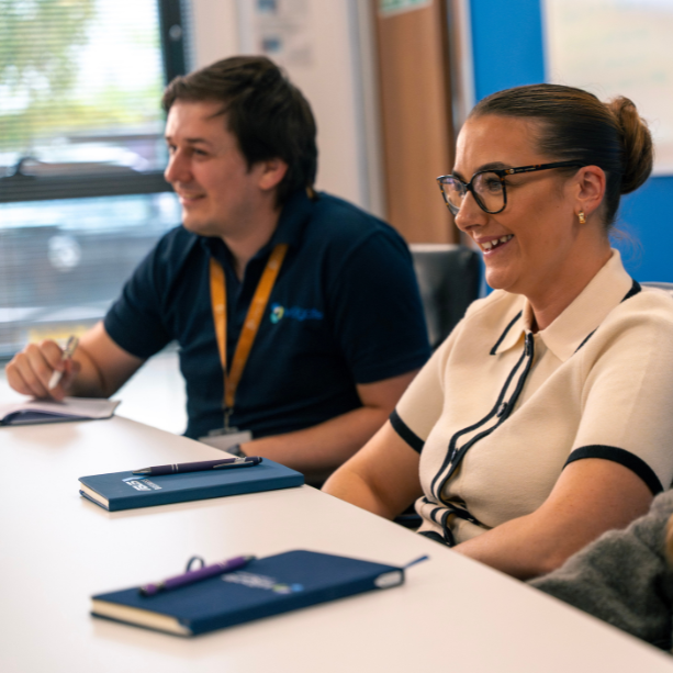 Team in a meeting at a table, they are smiling.