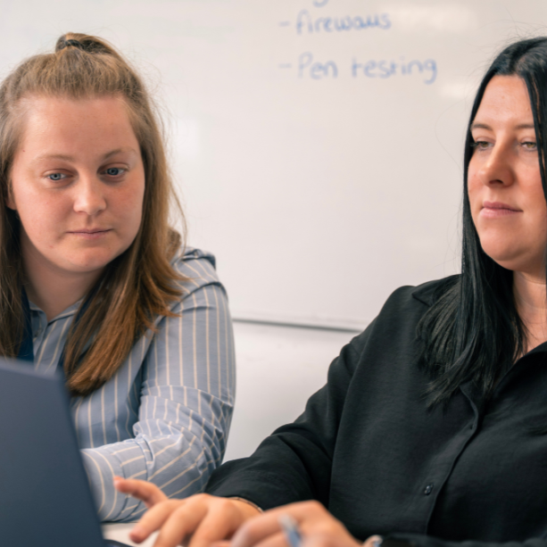 Two staff work together at a laptop.