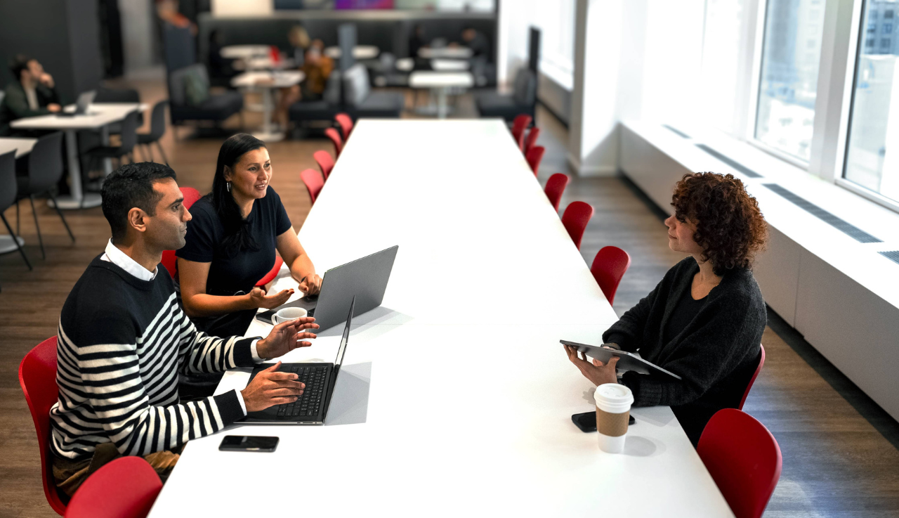 Group of staff say at a table in a meeting.