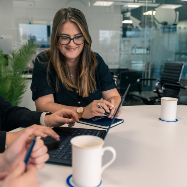 A female staff member smiles as she looks down at a laptop in front of her.