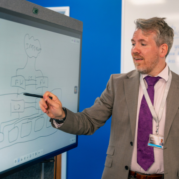 Staff member looking and points at a Neat board demonstrating a tech process.