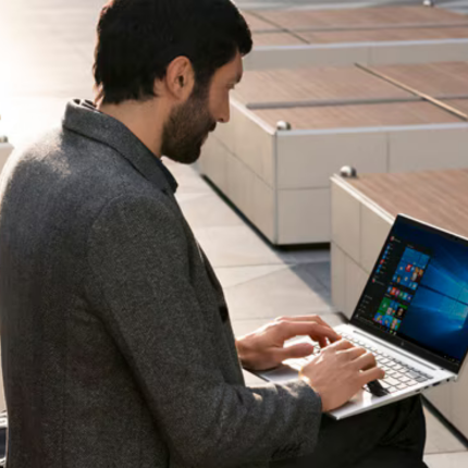 An over shoulder shot of a man sat with a HP laptop in his lap.