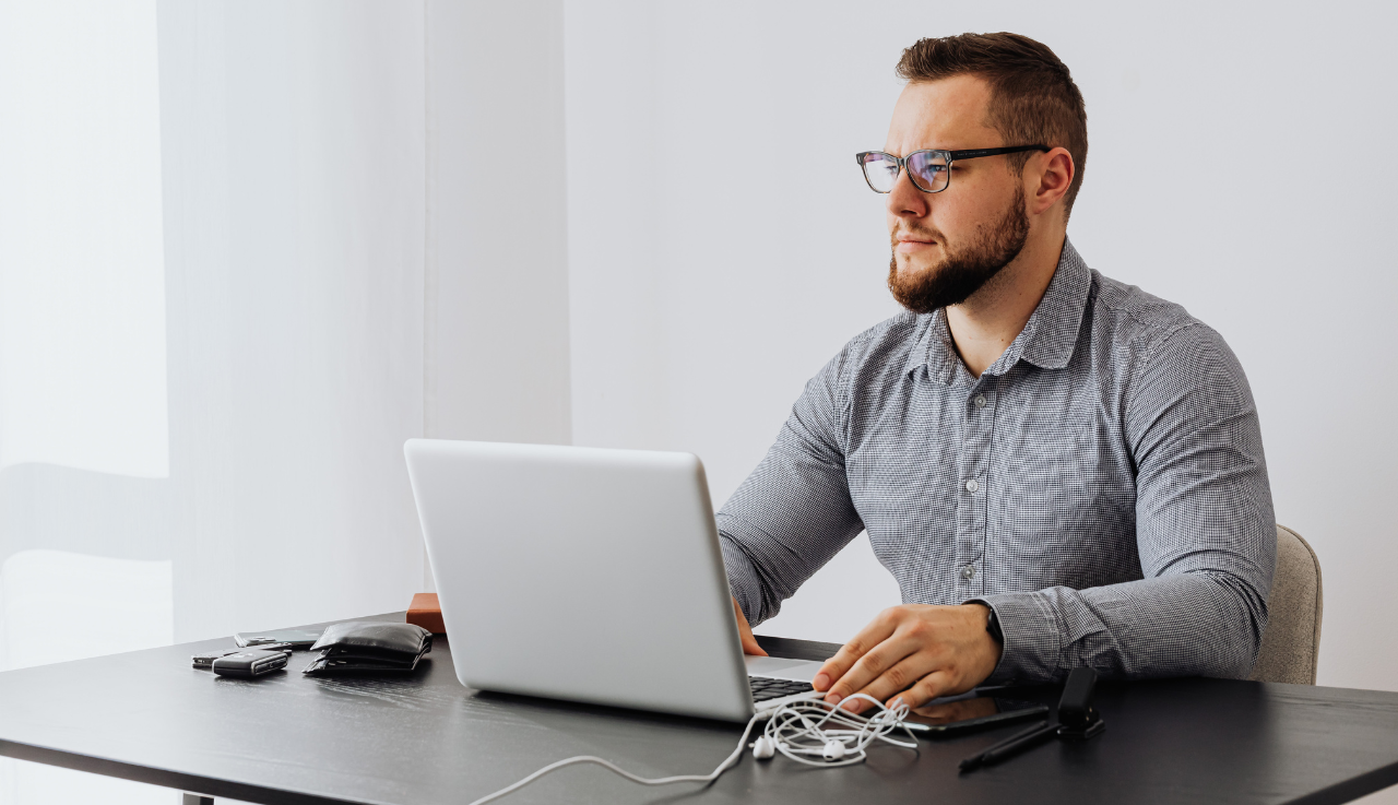 A man sits at his desk as he works at a laptop.