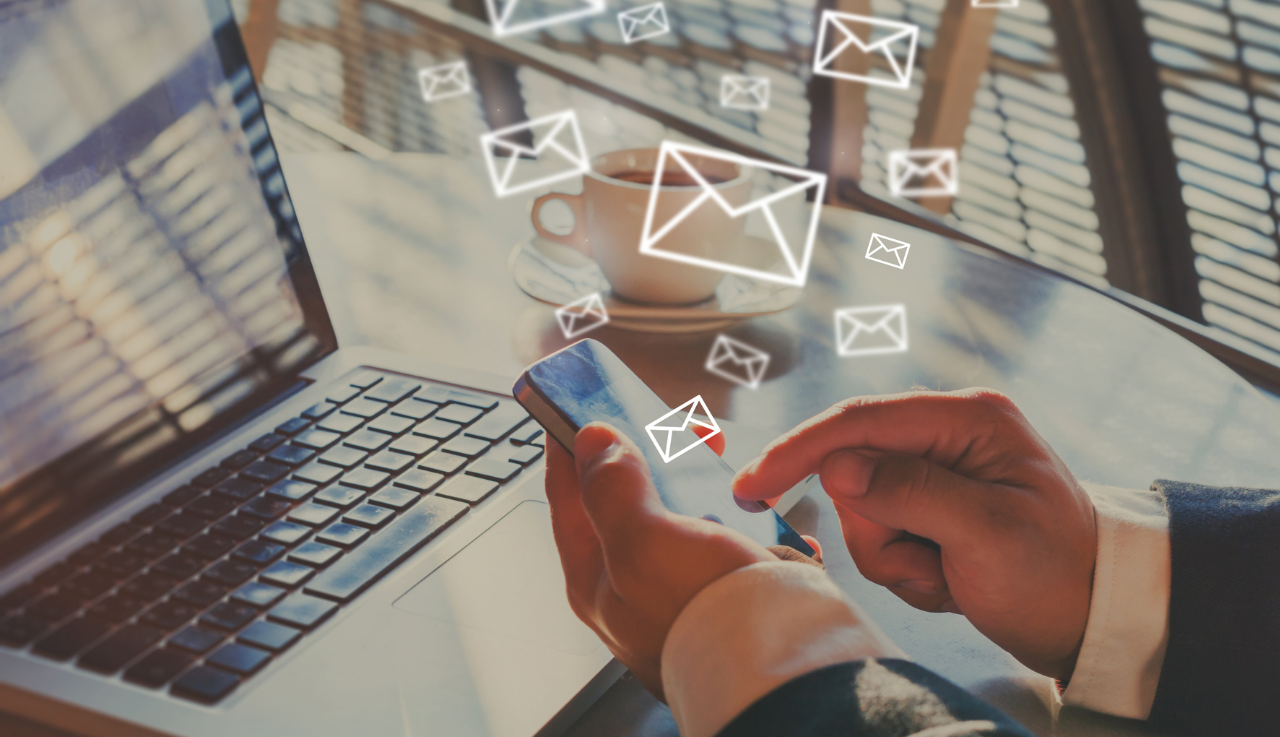 A person uses a phone to send emails.