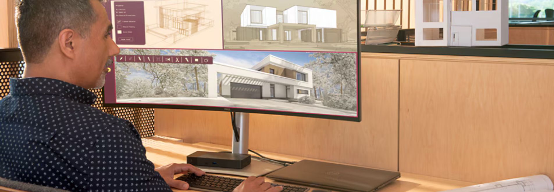 A man faces towards his desktop screen, away from the camera at his desk. He's looking at images of architecture. 