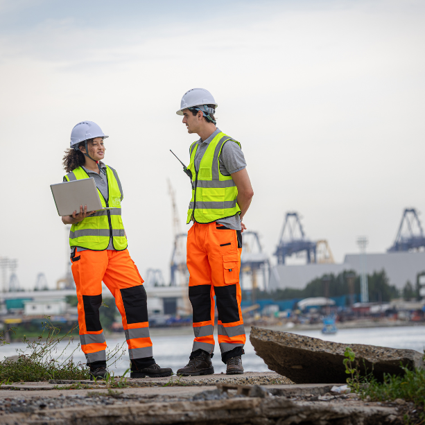 Two staff stood outside in high-vis and hard hats talking.