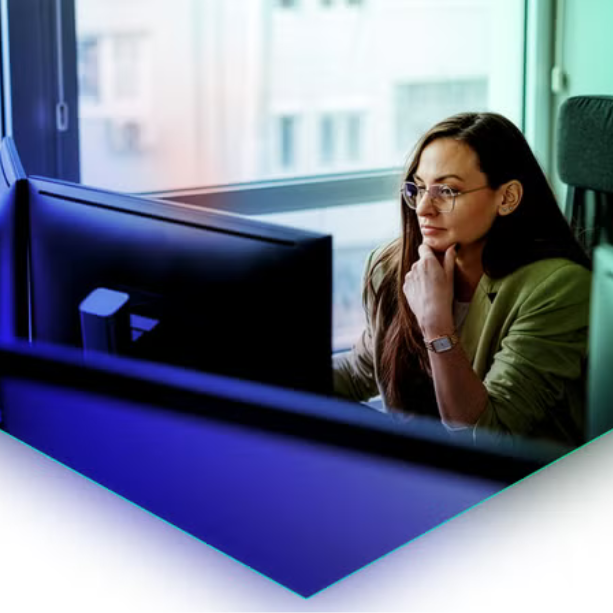 Woman sits at desk facing her desktop.