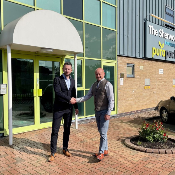 Sherwood press staff shake hands in front of the sherwood press building.