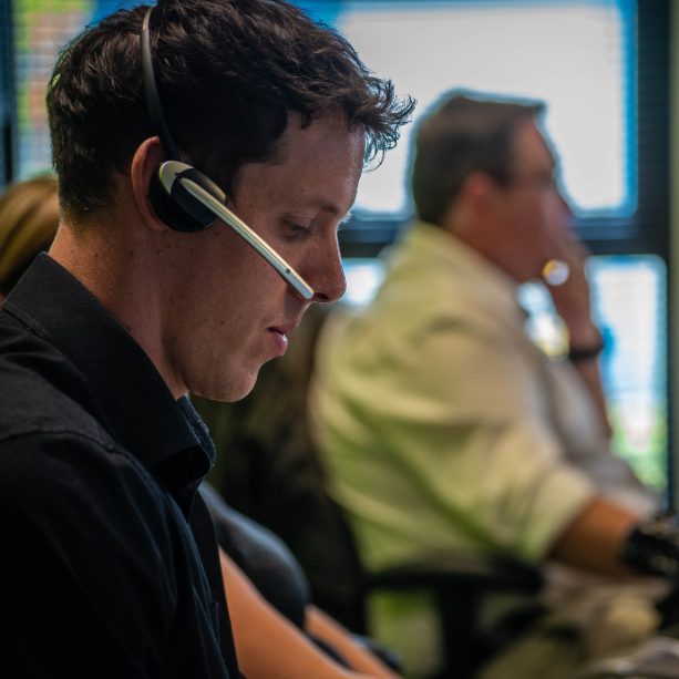 Close up of team member with a headset on looking down at this desk.