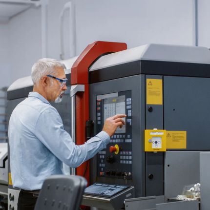 A man is using a screen on a production device in a factory.