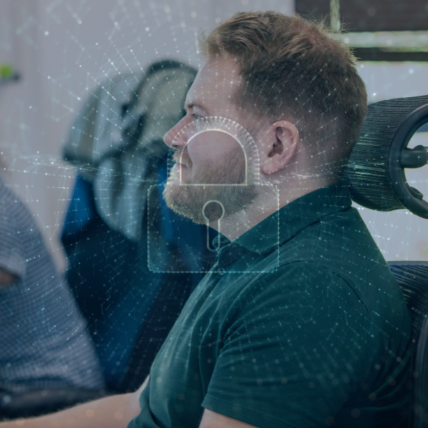 Cybersecurity manager at his desk. A graphic of a padlock sits atop the image.