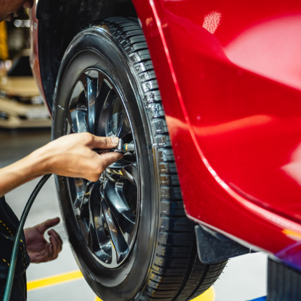 Someone holds an air pump to car wheel.