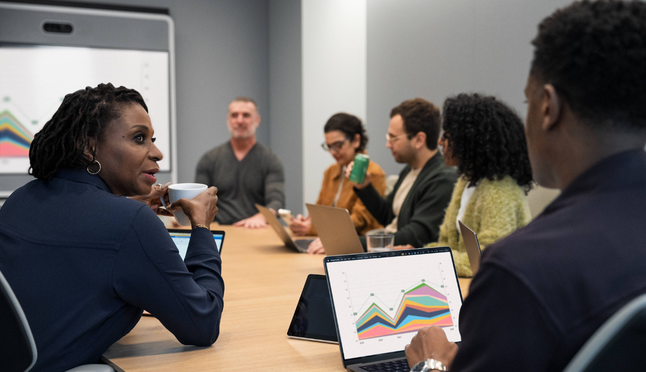 A group of staff in a team meeting, sat around a table.